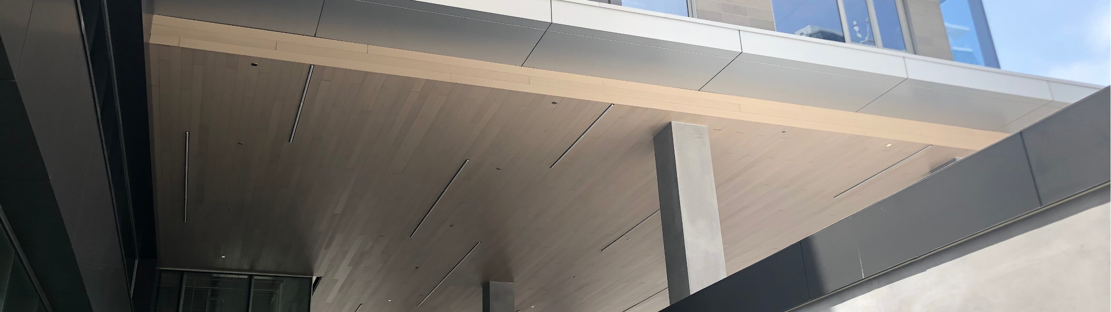 Commercial building overhang featuring composite soffit and ceiling panels with integrated linear lighting and contemporary design