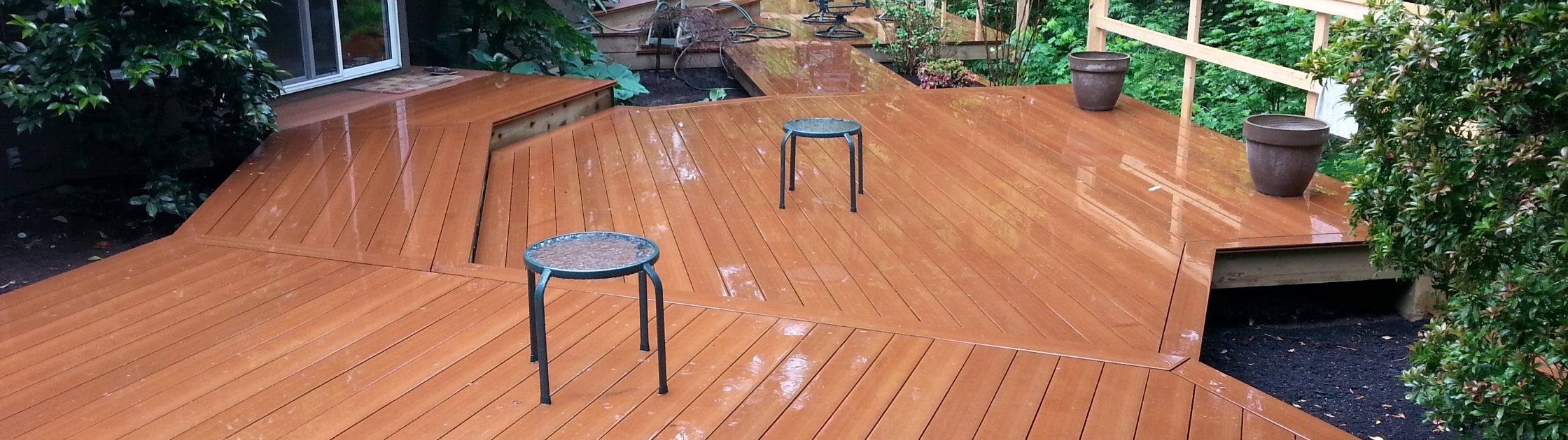 Custom multi-level composite decking installed in a landscaped backyard featuring angled deck board patterns and low-maintenance wood-look composite deck boards.